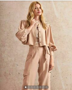 Características de la Chaqueta: Color: Tono neutro suave (beige, arena, etc. - especificar el tono exacto si lo conoces). Diseño: Corta a la cintura, cuello redondo, cierre frontal (cremallera o botones ocultos), mangas 3/4 abullonadas con puños elásticos o ajustados. Tejido: Textura suave y elegante (lino, mezcla de algodón, etc. - especificar si lo conoces). Estilo: Chic y moderno, ideal para combinar con pantalones de tiro alto o faldas.