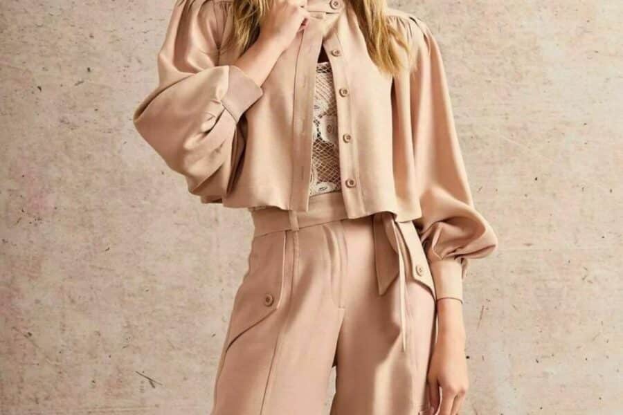 Características de la Chaqueta: Color: Tono neutro suave (beige, arena, etc. - especificar el tono exacto si lo conoces). Diseño: Corta a la cintura, cuello redondo, cierre frontal (cremallera o botones ocultos), mangas 3/4 abullonadas con puños elásticos o ajustados. Tejido: Textura suave y elegante (lino, mezcla de algodón, etc. - especificar si lo conoces). Estilo: Chic y moderno, ideal para combinar con pantalones de tiro alto o faldas.